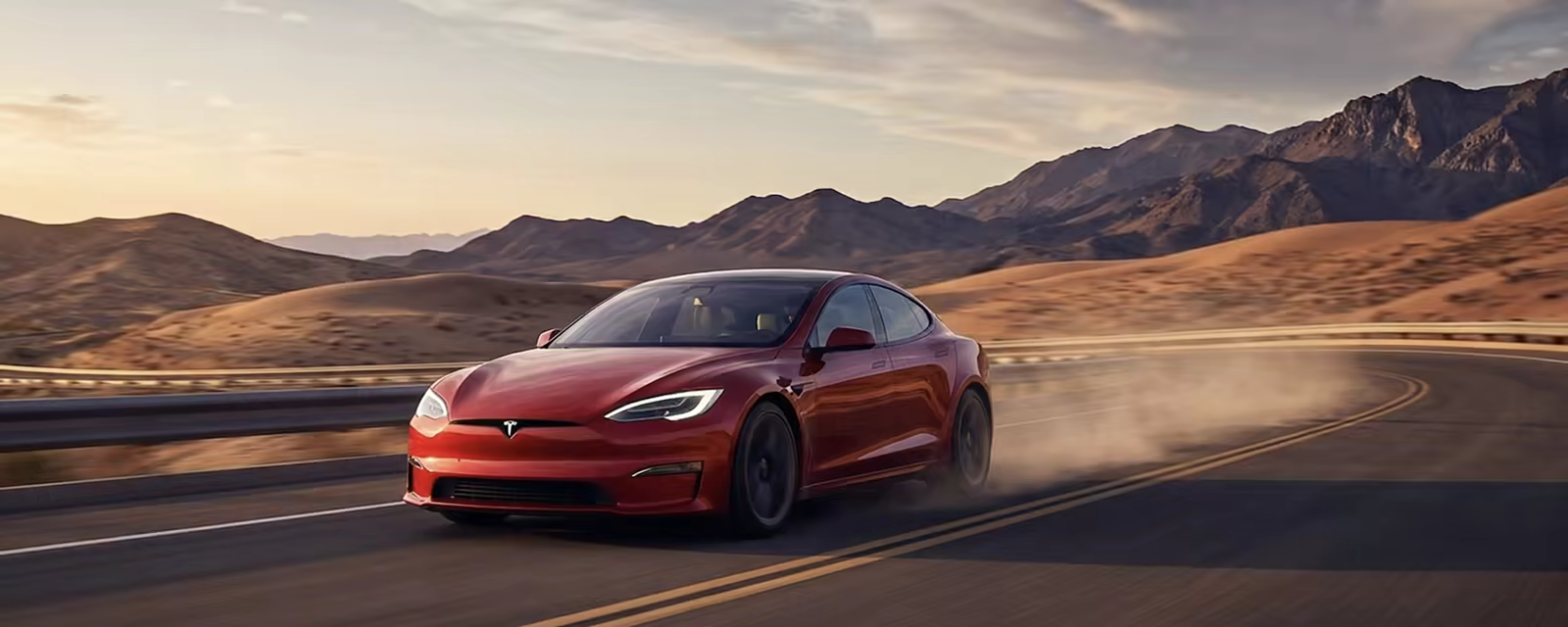 Tesla rojo en carretera al atardecer